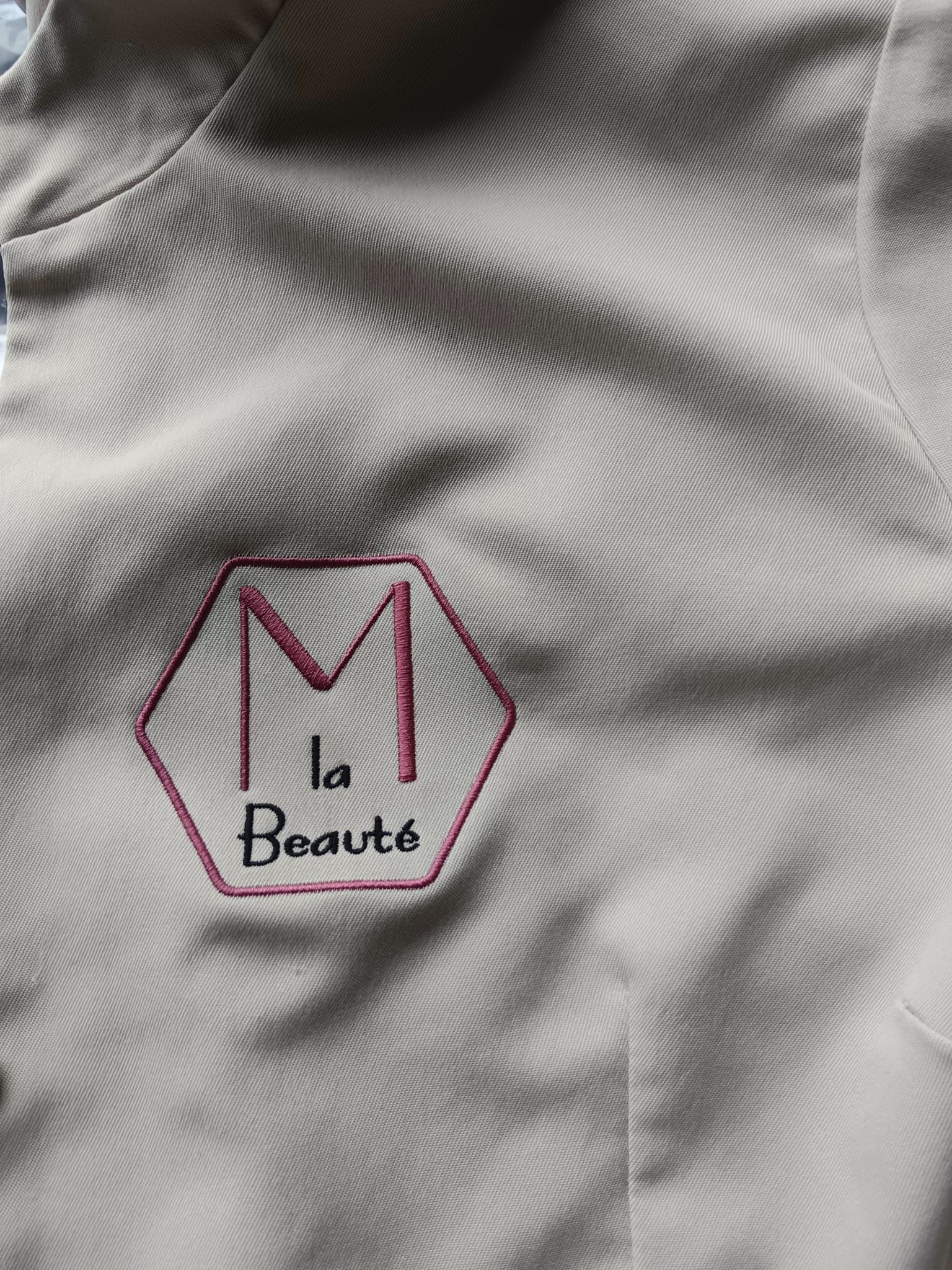 Blouse de travail brodée avec le texte 'M La Beauté' en lettres élégantes